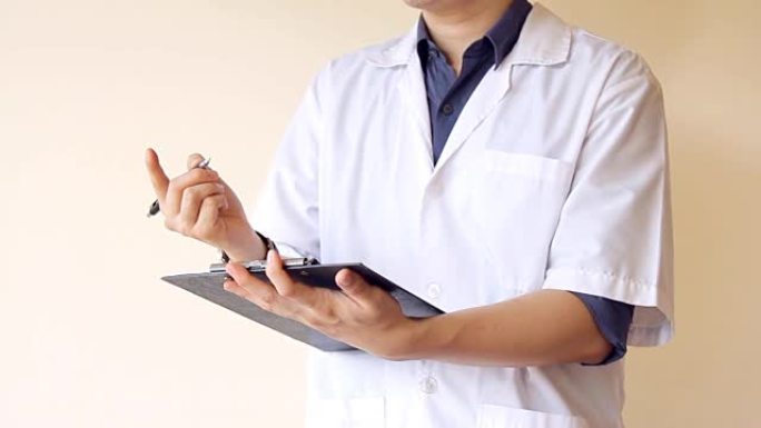 男医生在剪贴板上拿着病人笔记，写和讨论病人的症状