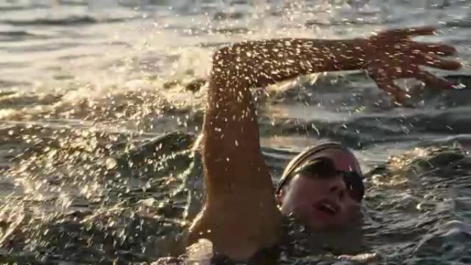 SLO MO夫妇在阳光下在海上游泳前爬行