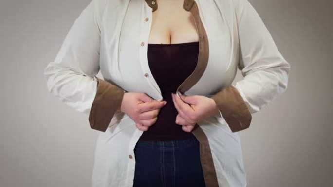 无法辨认的高加索胖女人扣紧衬衫。肥胖的成年女孩有超重问题。暴饮暴食，肥胖，不健康的生活方式。
