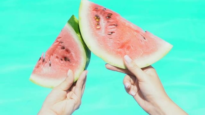 女人在游泳池旁碰着西瓜片，玩得开心，维生素水果