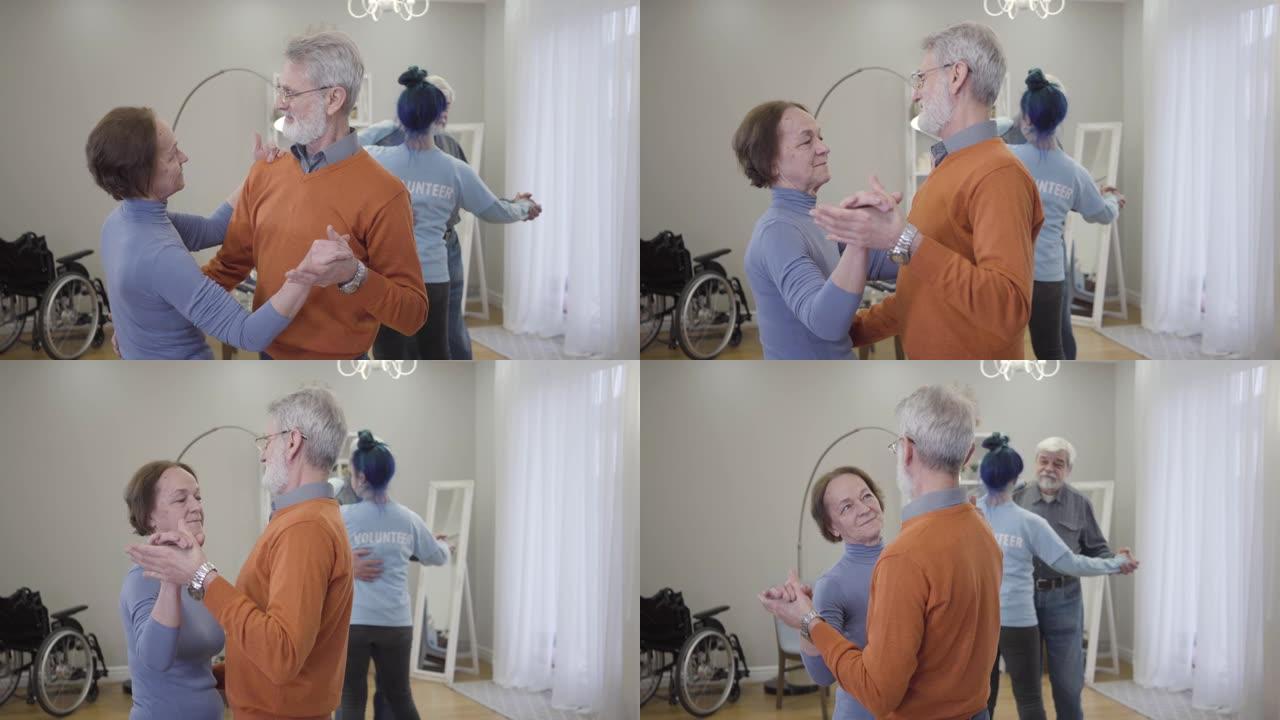 微笑的白人老男女在疗养院慢慢跳舞。快乐的退休人员在古典音乐的伴奏下跳华尔兹。
