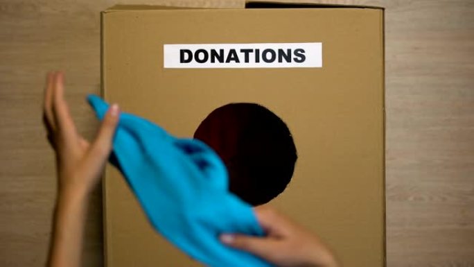 妇女将旧衣服放在纸板箱中进行捐赠，慈善组织