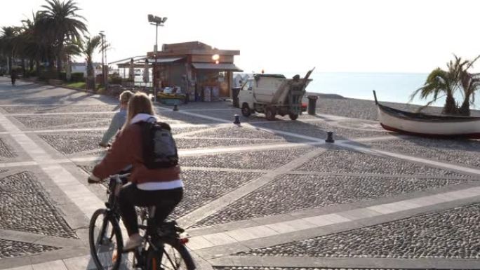 妇女沿着海滨长廊骑自行车