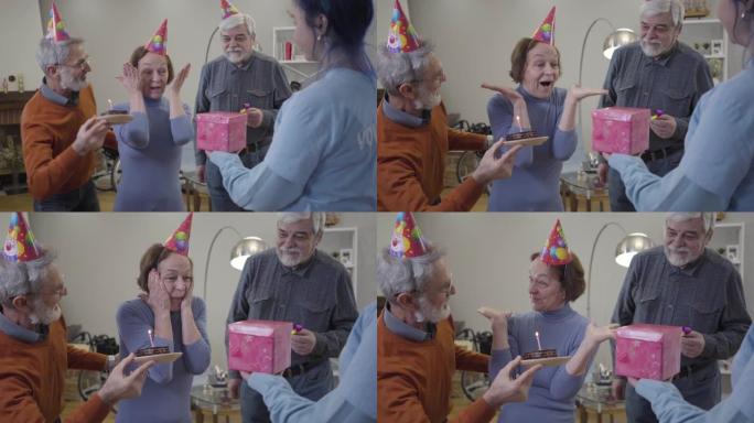 当志愿者和老人带来礼物和生日蛋糕时，激动的白人老妇睁开眼睛的肖像。在疗养院庆祝的女性退休人员。