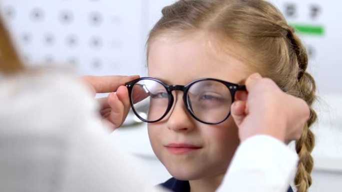 女眼科医生为微笑的小女孩选择眼镜，光学框架