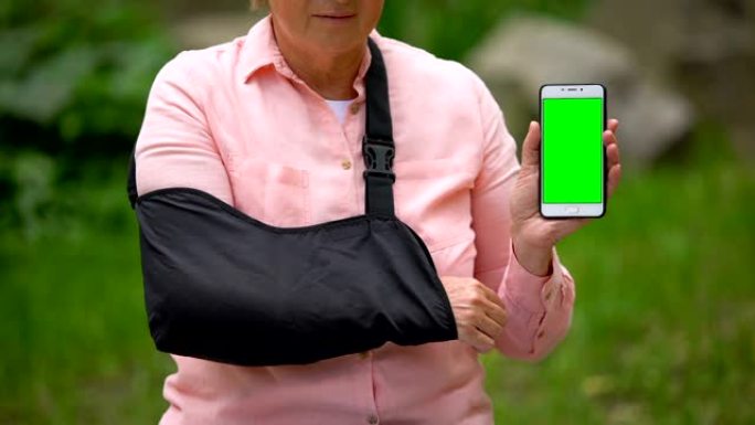 穿着肩膀固定吊带的高级妇女显示智能手机绿屏