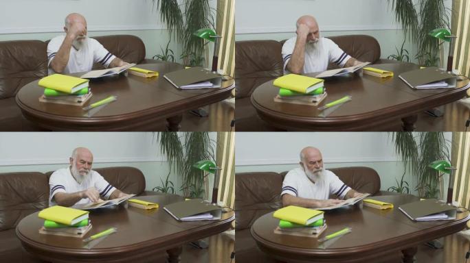 体贴的大胡子老人坐在皮沙发上的木桌旁看书。