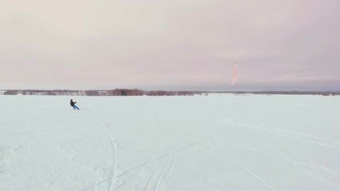 在冬季用滑雪板或滑雪板进行风筝冲浪。在风中在冰上溜冰。美丽的彩色的帆