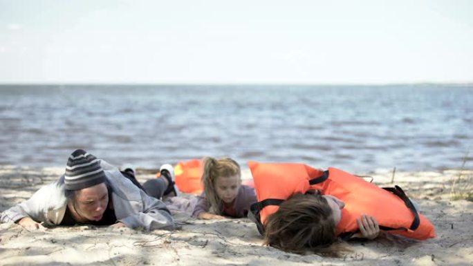 沉船后，难民幸存者在岸上吐水的妇女和儿童