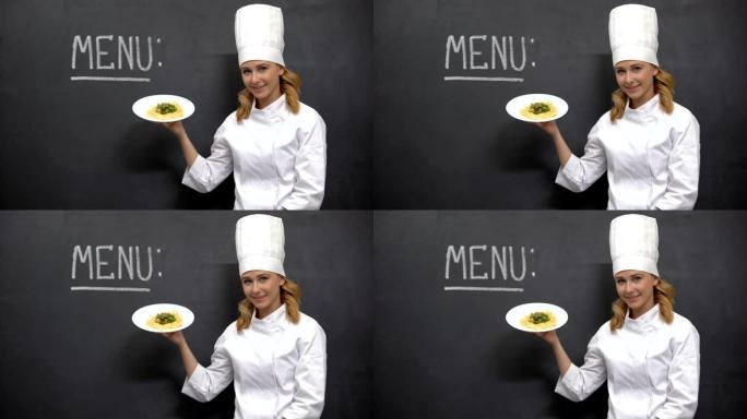 女厨师拿着面食盘，黑板上有菜单字，餐厅
