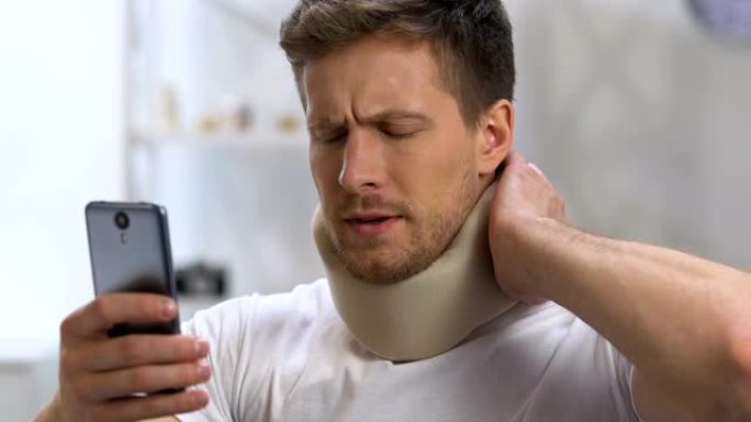 男戴颈圈抱手机突然感觉颈部剧烈疼痛