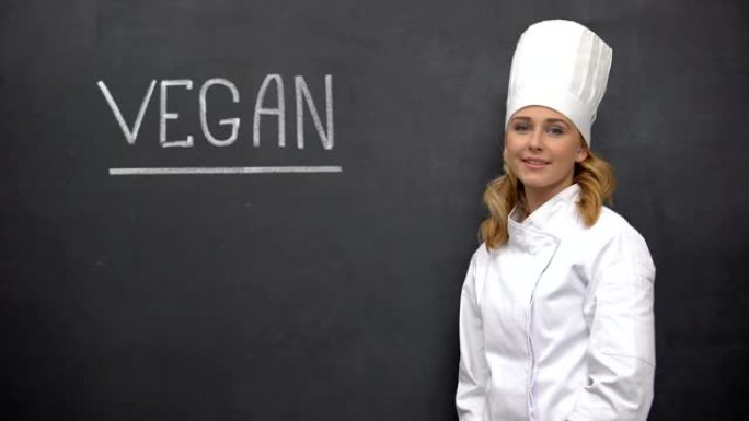 微笑的首席厨师站在素食主义者的黑板上，饮食学