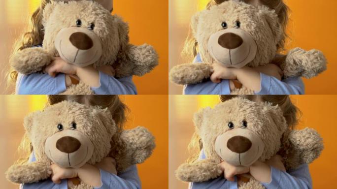 害羞的学龄前女孩躲在最喜欢的泰迪熊后面，童年心理学