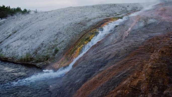 在怀俄明州的黄石国家公园，水从大棱柱形泉水的岩石表面掉入火坑河的慢动作镜头