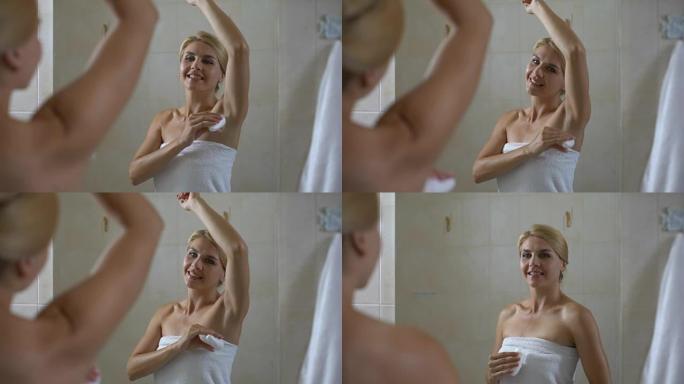 快乐的女性涂抹止汗剂和看浴室镜子，卫生