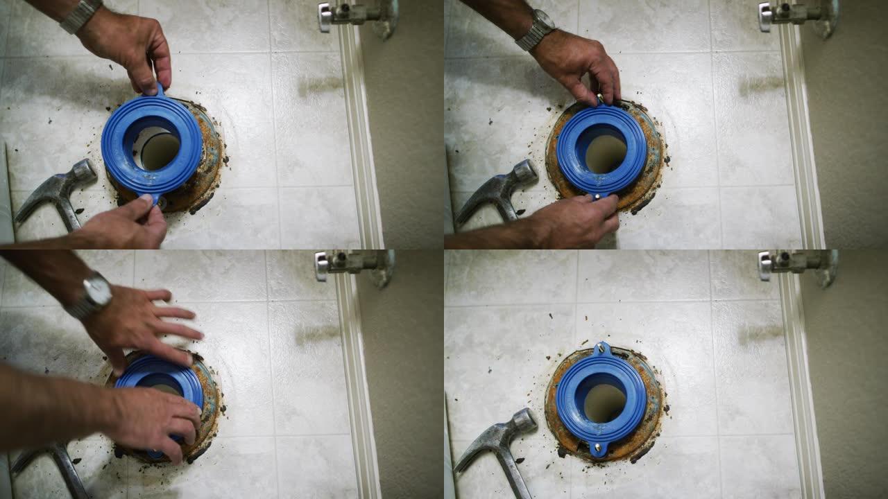一名高加索杂工将橡胶垫圈放在法兰螺栓上，同时将破损的马桶固定在室内家用浴室中