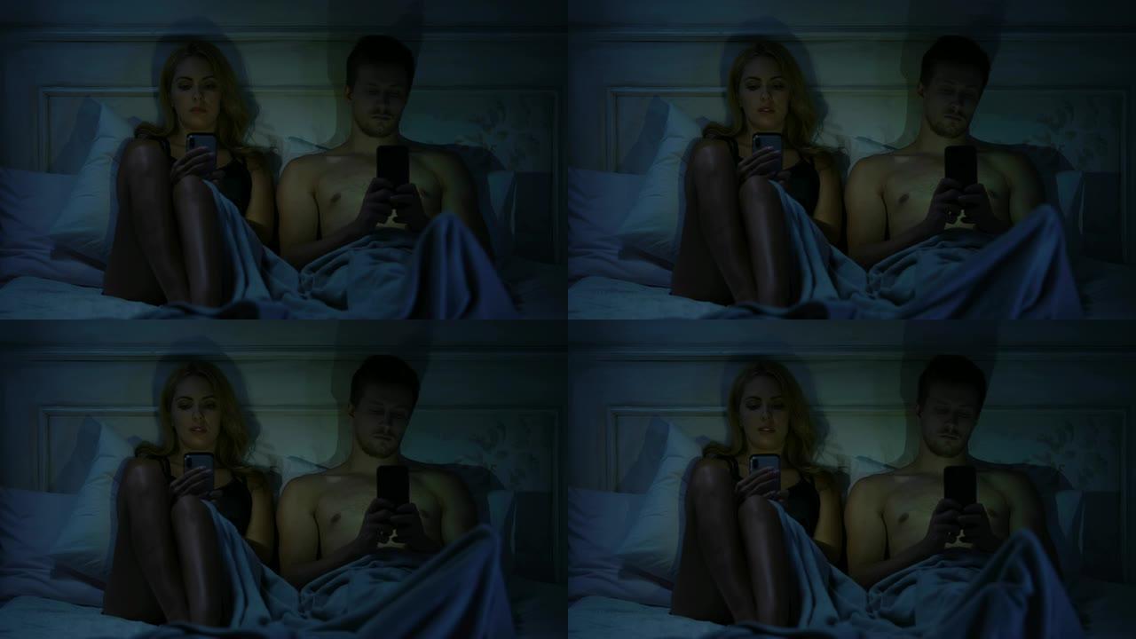 夫妇坐在床上，在智能手机上聊天，不说话，小工具成瘾
