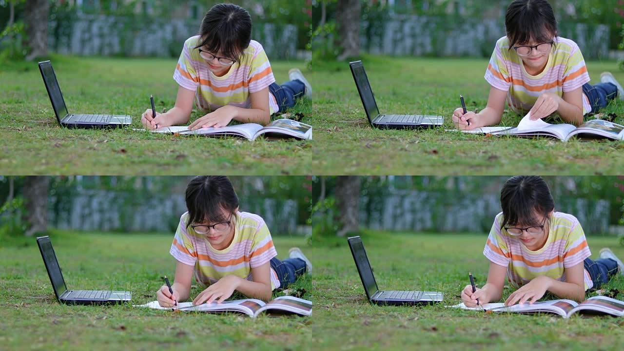 公园里微笑的亚洲女孩在树下看书