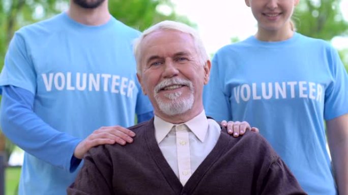 微笑的志愿者站在老残疾人身后，社会支持，慈善事业