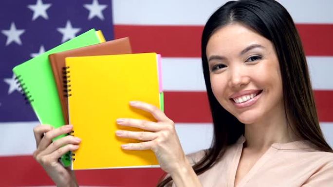 快乐的学生展示笔记本美国国旗背景，大学教育