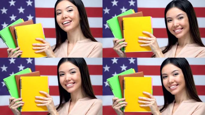 快乐的学生展示笔记本美国国旗背景，大学教育