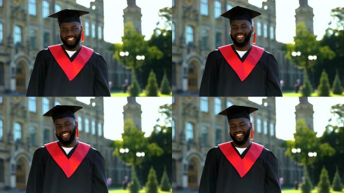 大学背景下毕业礼服微笑相机的满意黑人男性