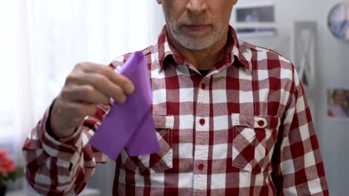 悲伤的老人拿着紫丝带，意识到癌症和阿尔茨海默病