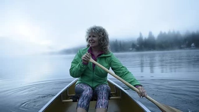 在原始湖上划独木舟的高级妇女