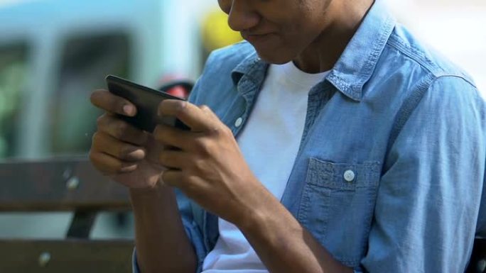 上瘾的非洲裔美国男性少年紧张地在智能手机上玩视频游戏