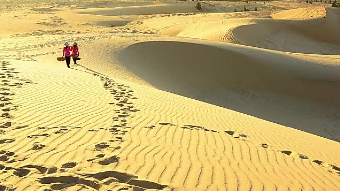 两名越南妇女带着柳条篮子在沙丘上行走