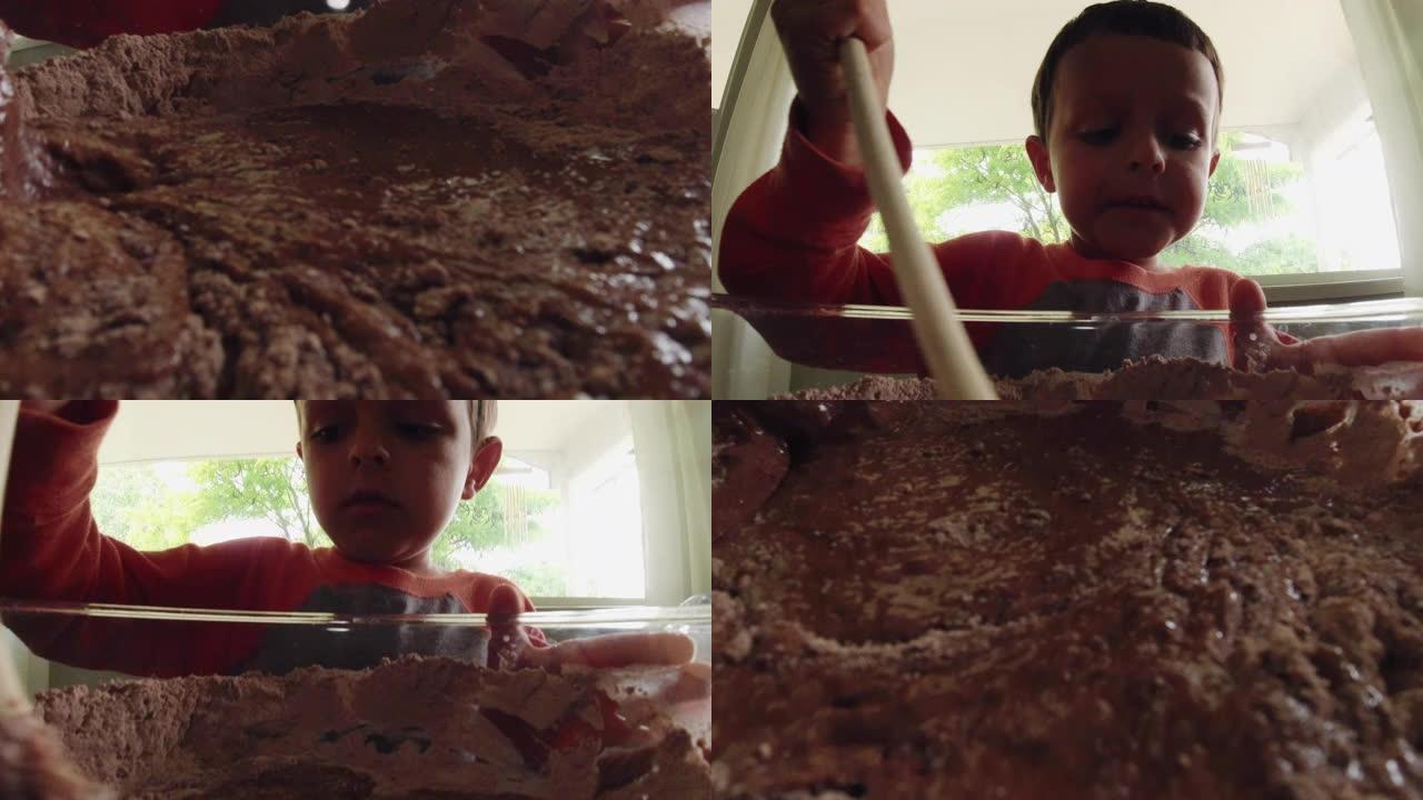 一个可爱的六岁白人男孩在室内厨房烘烤时，用木勺将湿的和干的成分混合在一个大玻璃碗中