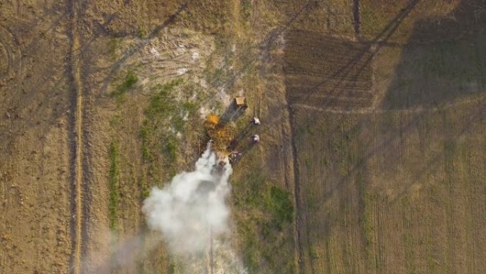 老高加索男人和女人燃烧干燥的落叶和树枝的俯视图。农民在田间生火的鸟瞰图。生态危害、污染、反生态生活方