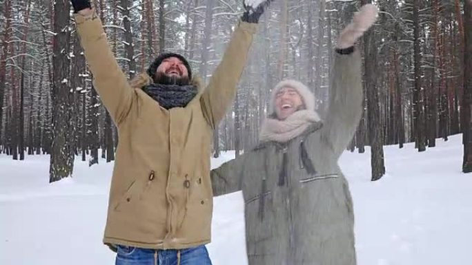 浪漫的男人在与妻子散步时向空中扔了一把雪