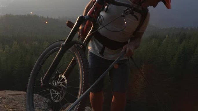 成熟的男性山地自行车手使用牵引绳进入小径