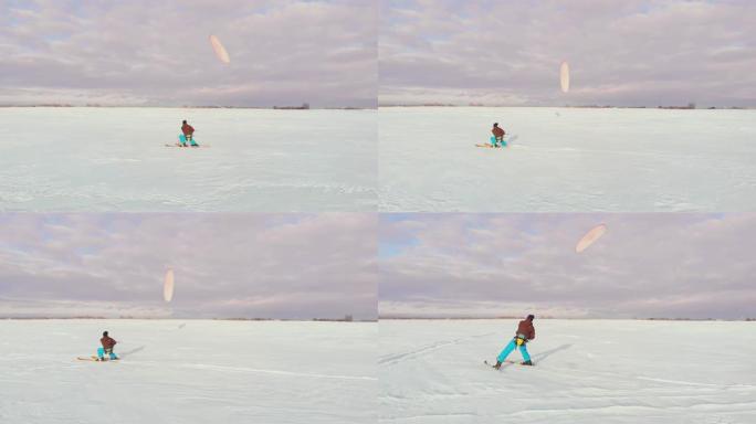 日落时，一个人在雪地里滑雪。他的降落伞拉了。风筝在雪地里冲浪