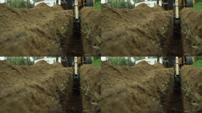 挖沟机在仓库附近的室外地面上切开一条沟渠