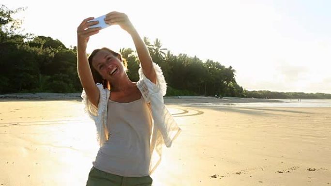 美丽的女孩在海滩上使用手机自拍