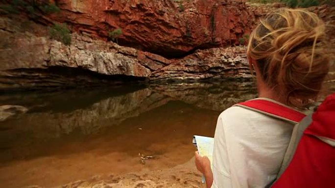 在内陆徒步旅行的年轻女子阅读地图寻找方向