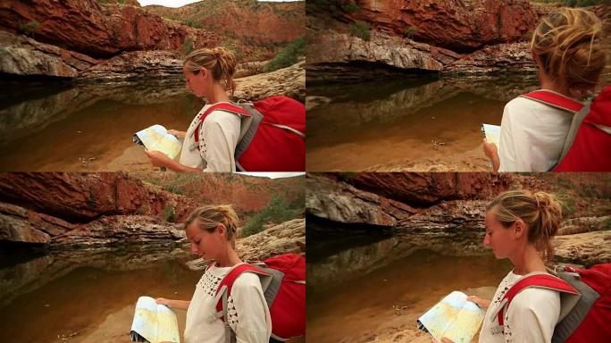 在内陆徒步旅行的年轻女子阅读地图寻找方向