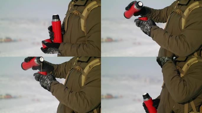 Man pours tea from a thermos winter