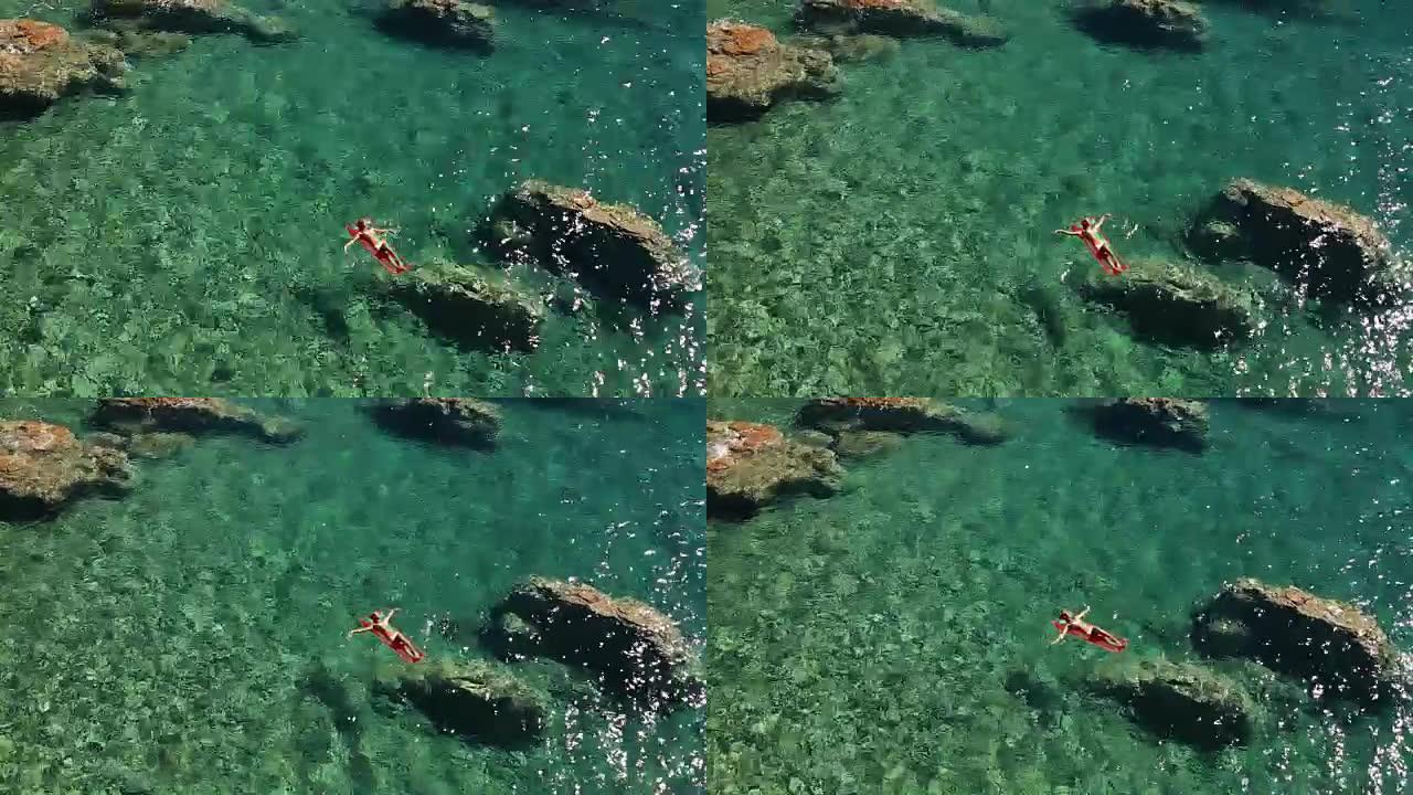 漂浮在海洋中的泳池床垫上的年轻女子