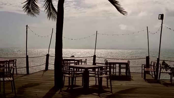 木地板上的木桌和木椅，椰子树和晴朗的天空和蔚蓝的大海。