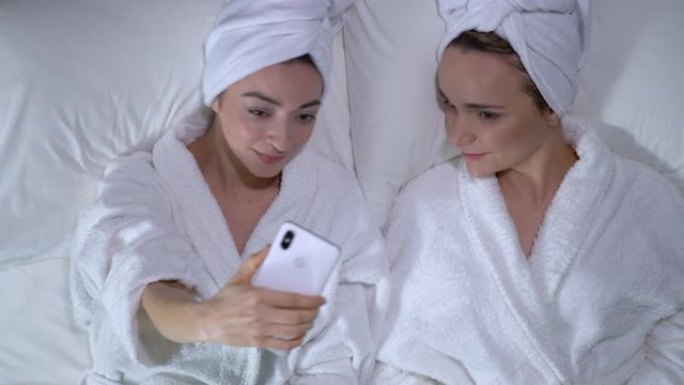 女性情侣在智能手机上自拍，在水疗中心享受浪漫约会