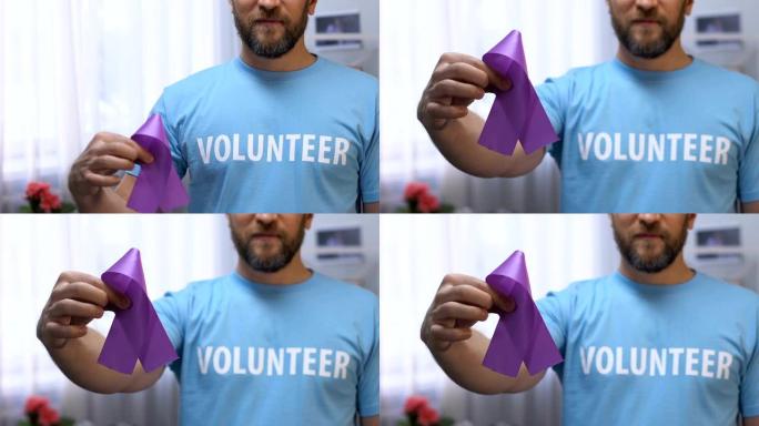 男性志愿者手拿紫丝带，对癫痫和胰腺癌有认识