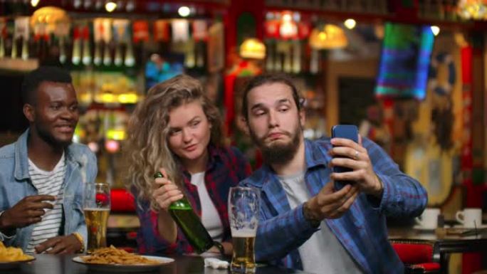 一群朋友男人和两个女孩在酒吧里笑着拍照。在酒吧和傻子在一起。
