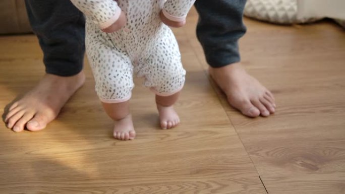 4k慢动作，父亲和母亲互相帮助，婴儿开始走路。