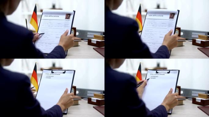 移民检查员拒绝签证申请，德国国旗在桌上，大使馆