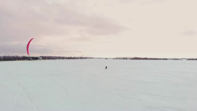 4k空中冬季极限运动雪地风筝比赛，在暴风雪和无人机的雪天气下，在城市前面的冰湖上，用不同的彩色风筝、