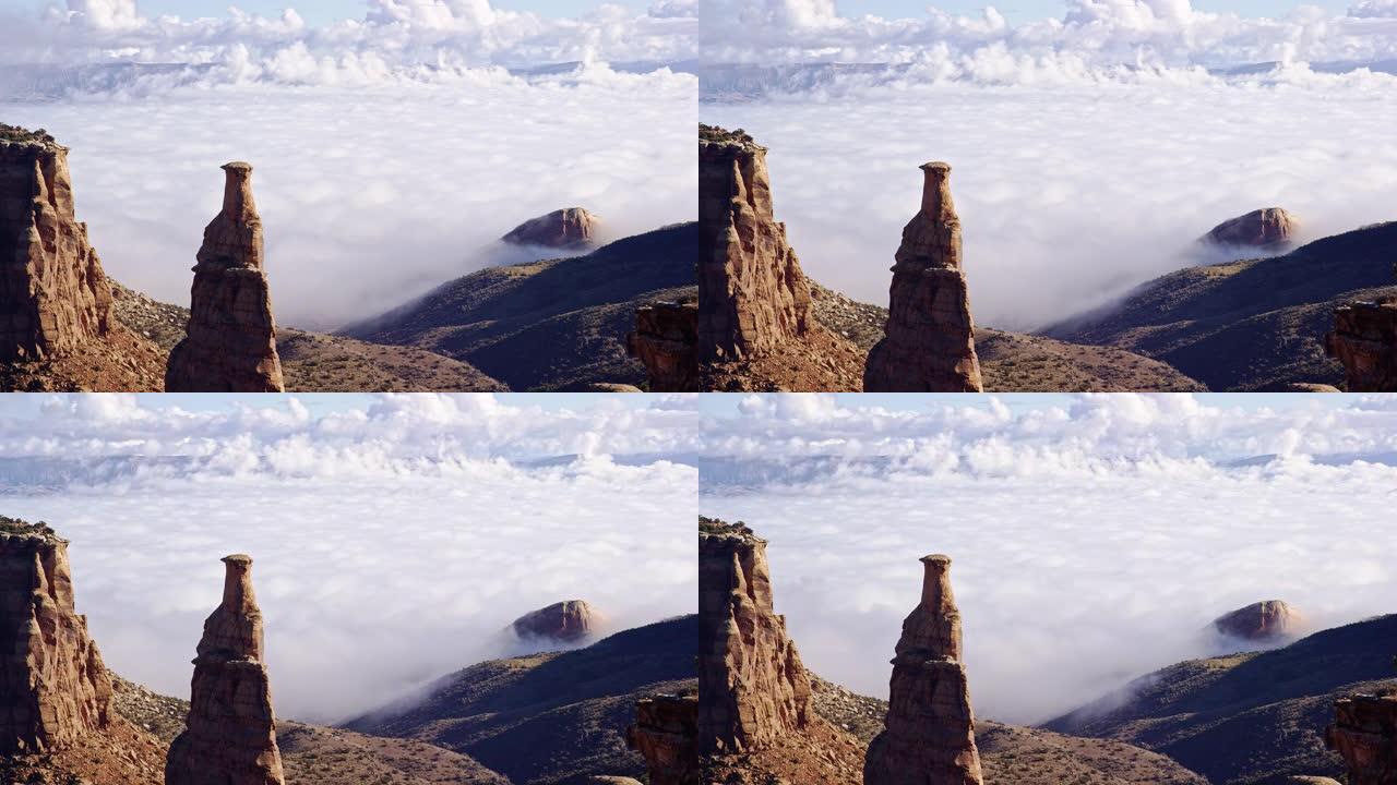 乌云/雾的倒转在科罗拉多州西部的大山谷上的时光倒转，前景是独立岩和科罗拉多国家纪念碑