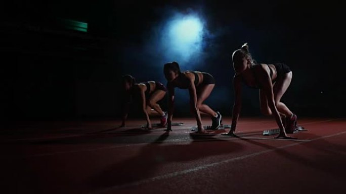 田径比赛的女跑步者在比赛前蹲在起跑区。慢动作